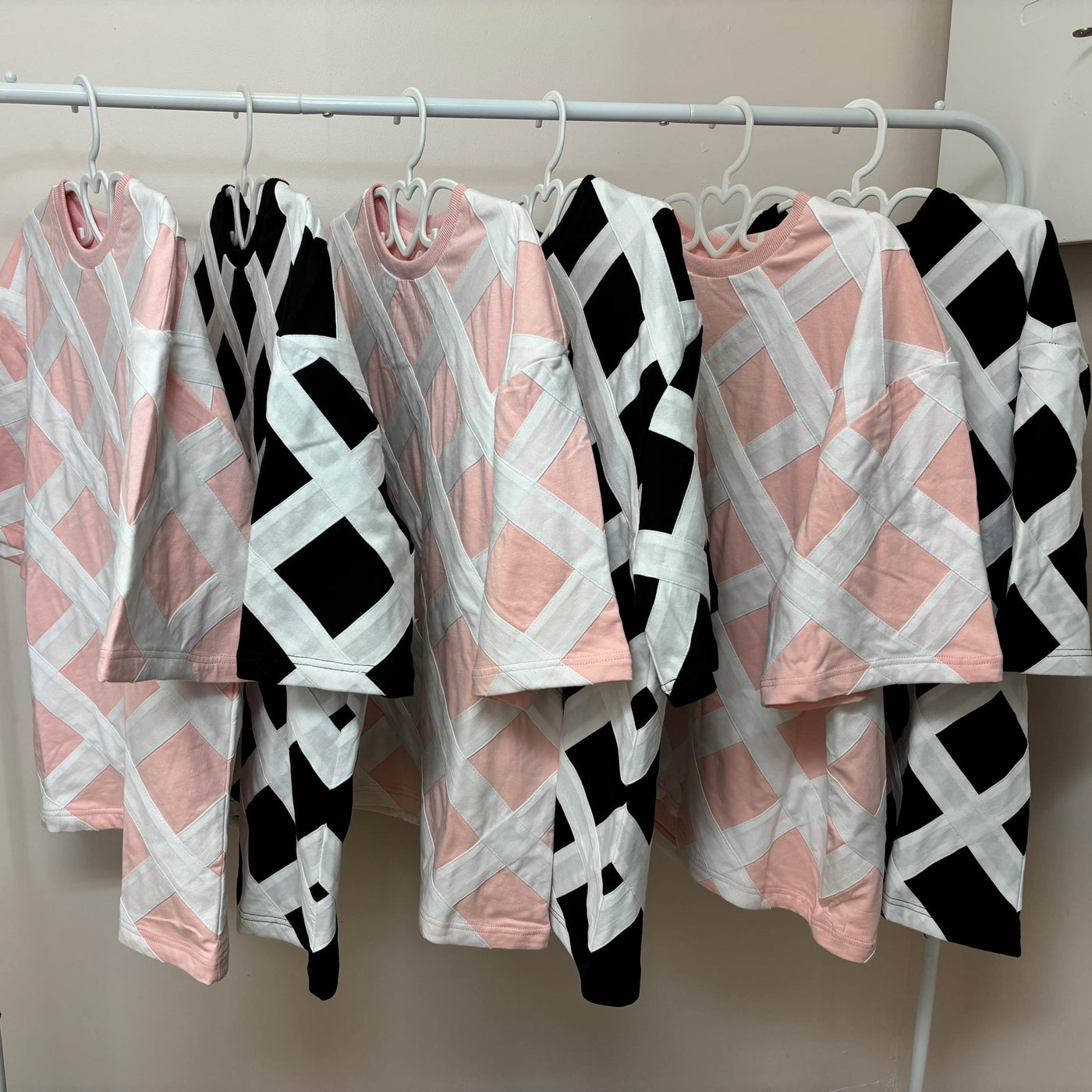 Pink and black lattice tees hanging together on a rail