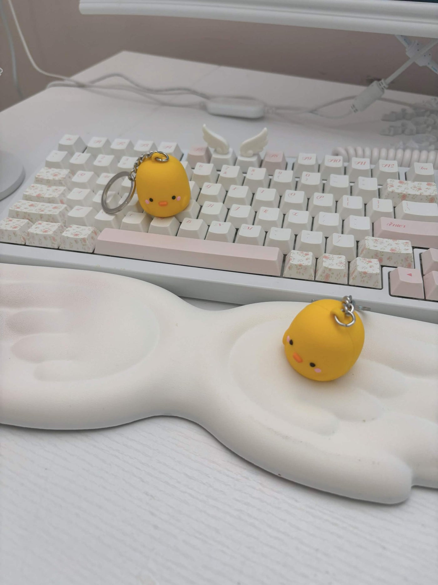 Two small yellow Henry keychains resting on a white keyboard