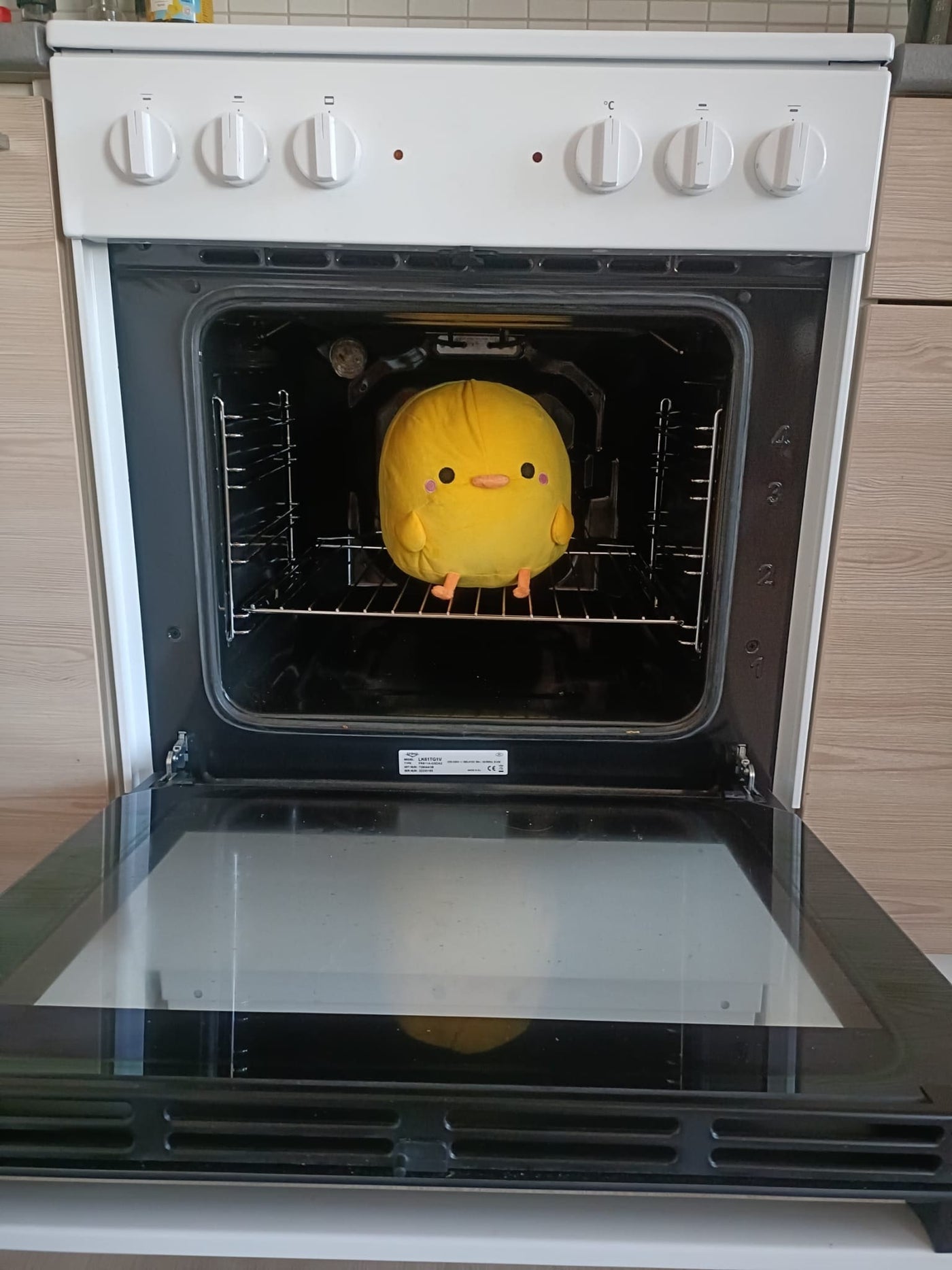 Henry plush sitting inside an open oven as a product disclaimer joke